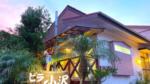 A building with a sign reading "OZAWA" and a person standing on a wooden platform. - Villa Ozawa (Shimoda)