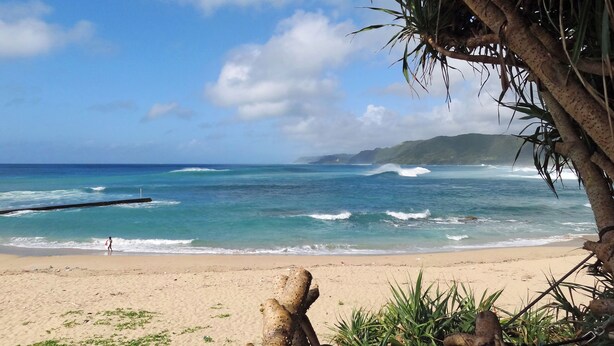 A beach with clear blue water, a sandy shore, and a distant mountain range. - Villa Tsumugu (Izumo)