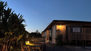 A building with a stone wall entrance, a sign with Japanese characters, and a well-lit exterior. - Villa Tsumugu (Izumo)