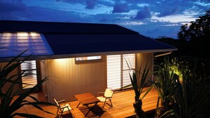 A modern house with a wooden deck, a small table, two chairs, and a window. - Villa Tsumugu (Izumo)