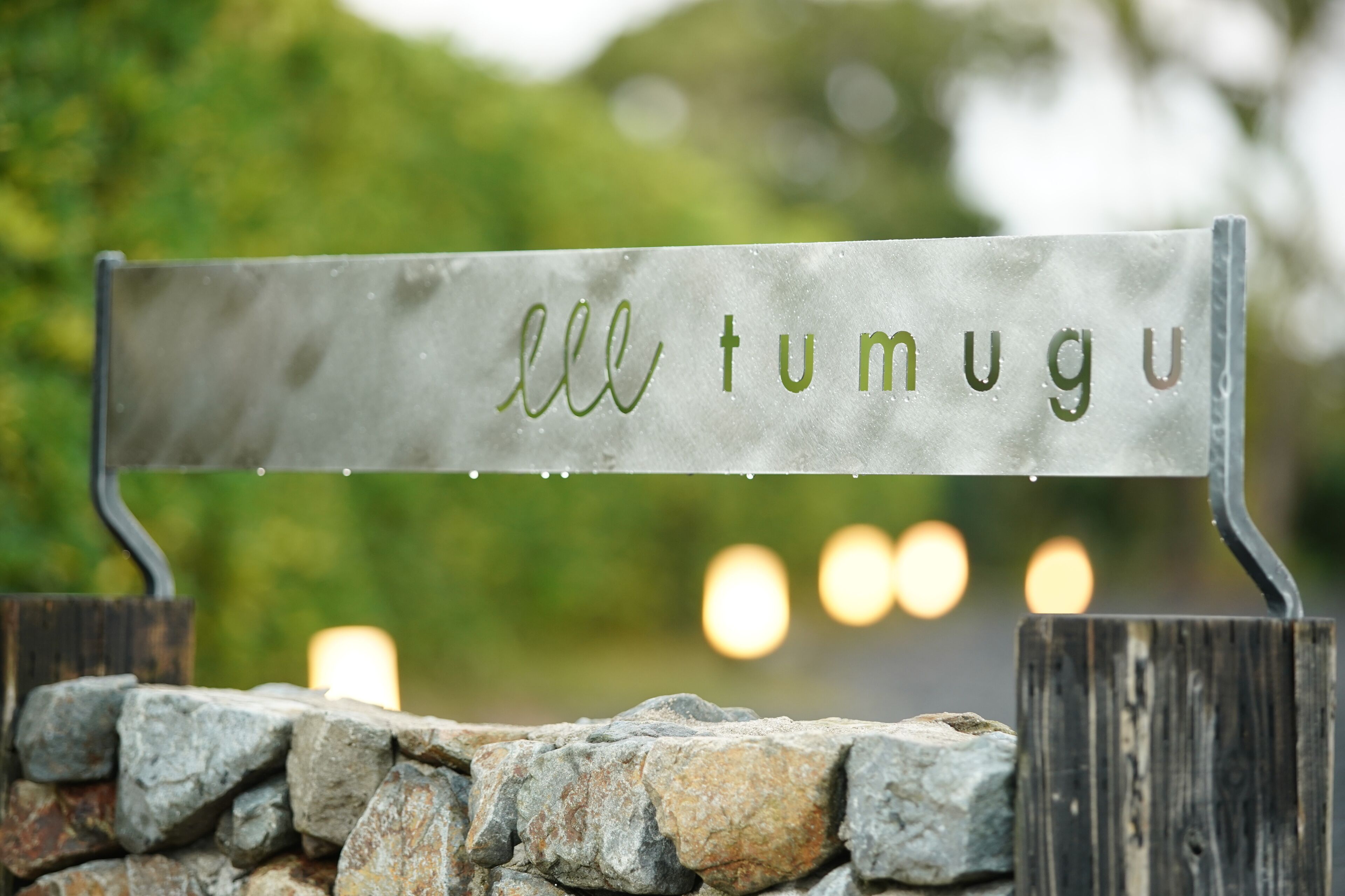 A metal sign with the text 'ell tumugu' mounted on a wooden post.