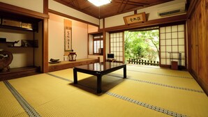 Una habitación japonesa tradicional con suelo de tatami, una mesa baja, puertas correderas y techo de madera.