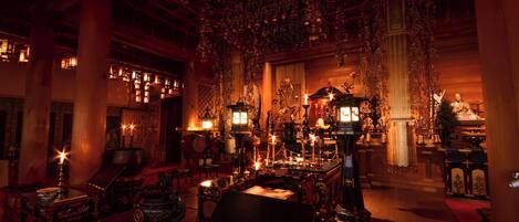 Un interior ornamentado con decoración tradicional, que incluye un gran altar, adornos colgantes y una mesa central.
