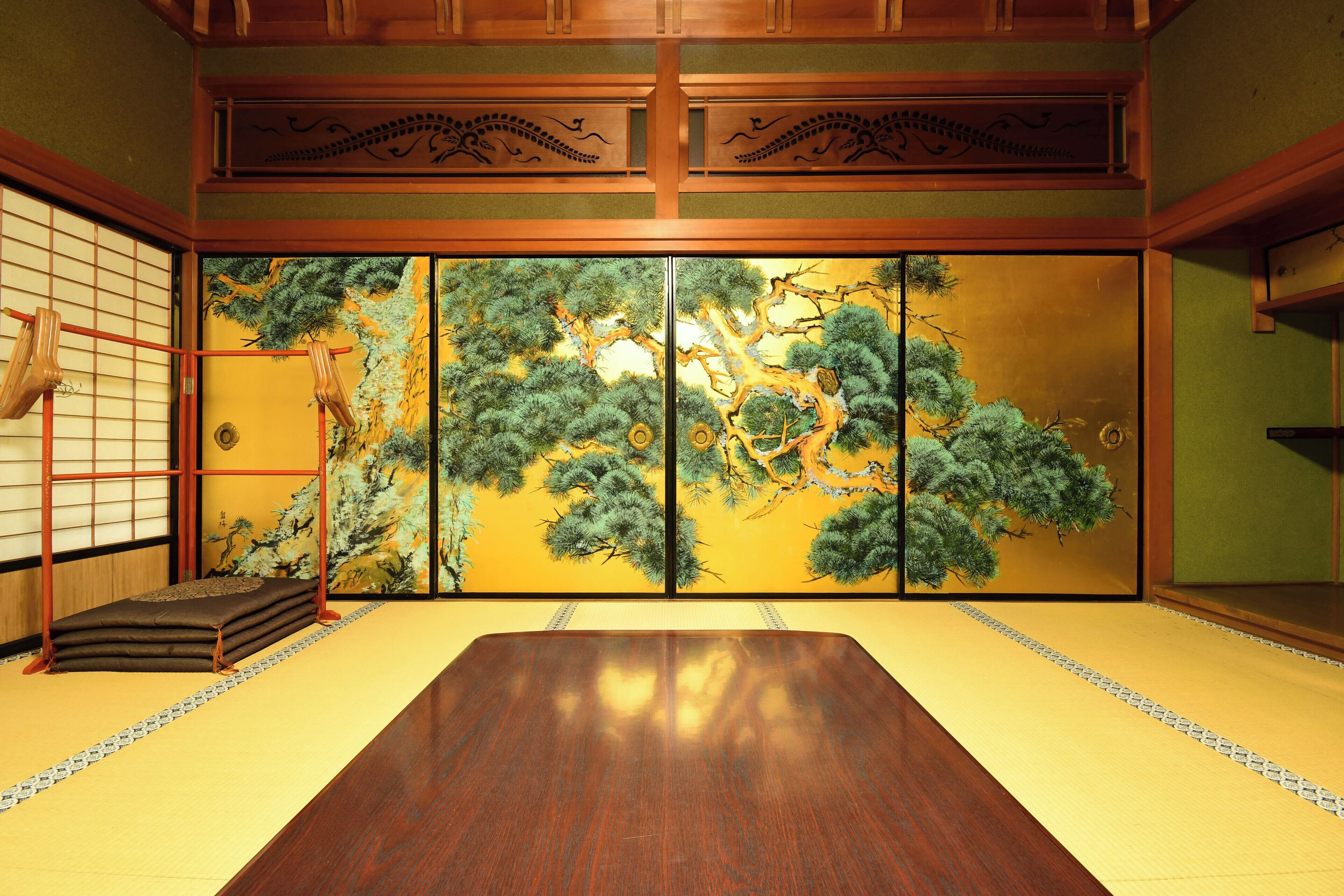 A traditional Japanese room with tatami flooring, a low wooden table, and a sliding door with a nature-themed mural.