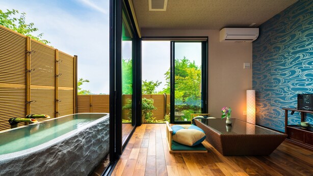 Ein modernes Badezimmer mit einer großen Badewanne, Holzboden und Blick ins Grüne.