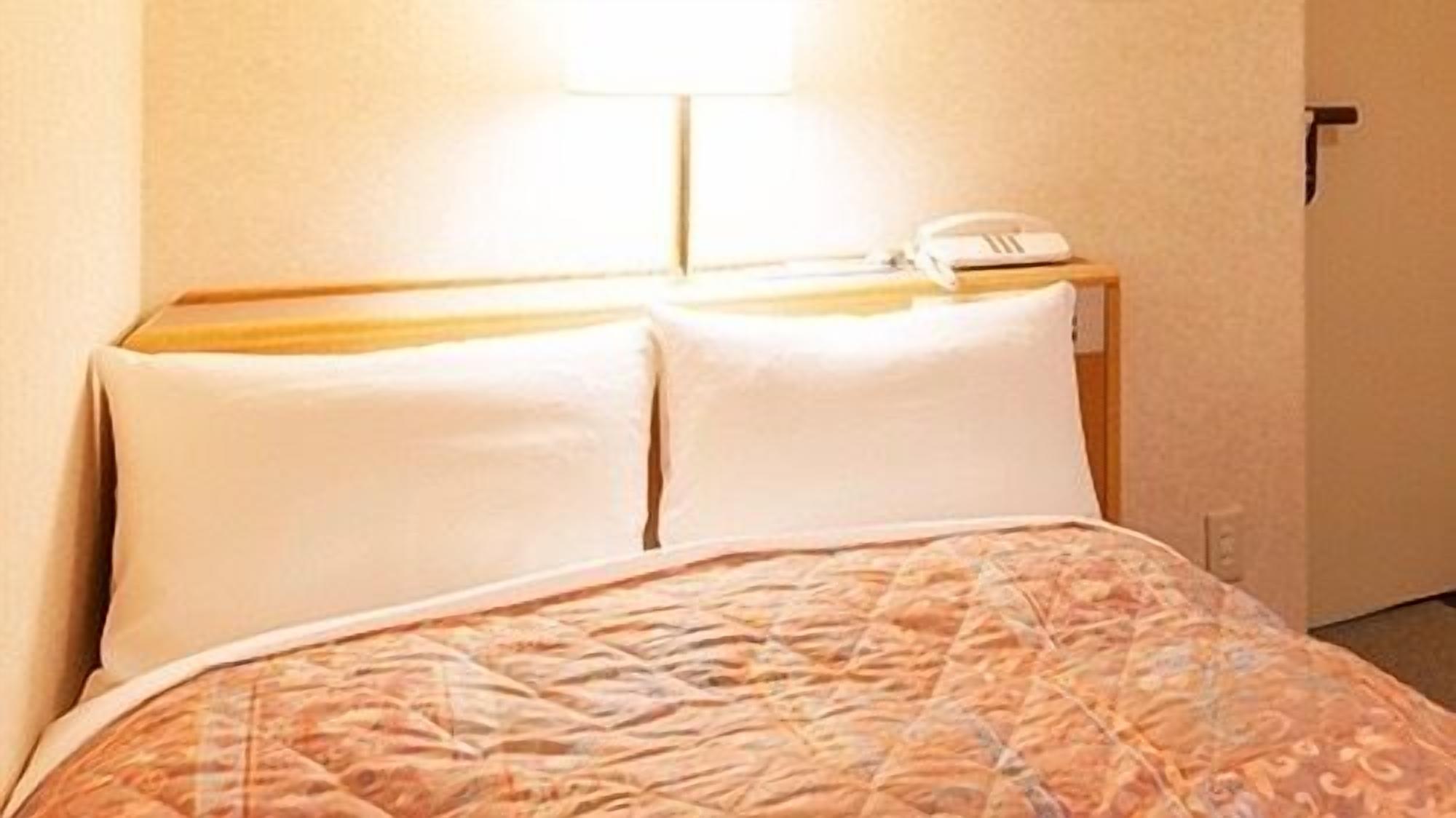 Ein Hotelzimmer mit Bett, Nachttischtelefon und Wandlampe.