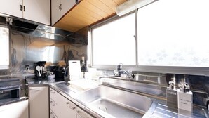 Une cuisine moderne dotée d’appareils électroménagers en acier inoxydable, d’un grand évier et de meubles blancs.
