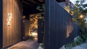 A modern building with a wooden facade and a stone wall entrance. - Akiba Nanguan (Susami)