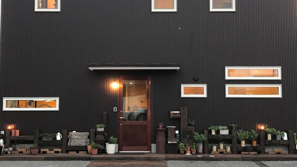 Un bâtiment moderne à la façade sombre, doté de nombreuses fenêtres et d’une entrée accueillante.