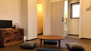 Une pièce comprenant une commode en bois, un téléviseur, une petite table et deux coussins.