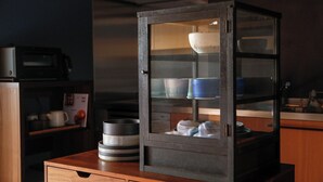 Une cuisine avec un comptoir en bois, un four à micro-ondes et un meuble vitré contenant de la vaisselle.