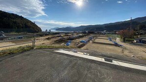 A parking lot with blue tarps and a clear sky. - Sanriku Active (Ofunato)