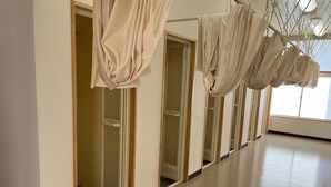 A hallway with mirrored doors and hanging fabric structures. - Sanriku Active (Ofunato)