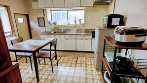 Une cuisine compacte comprenant une table à manger, des chaises, un réfrigérateur, un four à micro-ondes et un cuiseur à riz.
