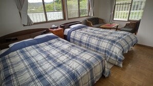 Une chambre avec deux lits, une table de chevet en bois, une petite table et une chaise.