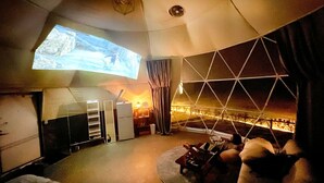 En ombonad inredning med ett stort fönster, en projektorduk och en sittgrupp.