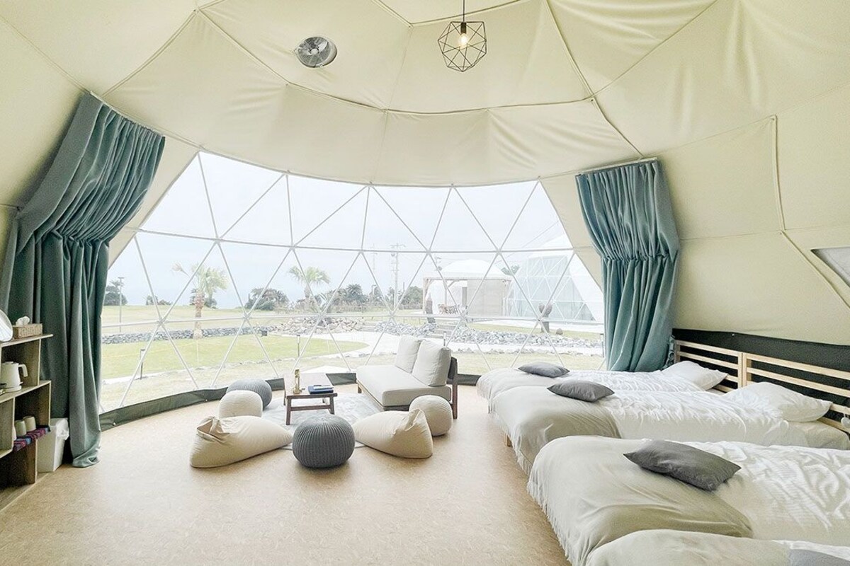 A tent-style room with three beds, a sofa, and a small table.