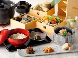 Presentación tradicional de comida japonesa con diversos platos en cajas y cuencos de madera.