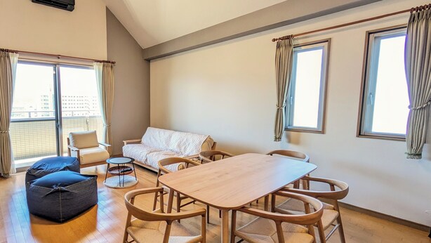 Un salon spacieux avec une table à manger en bois, des sièges confortables et de grandes fenêtres.