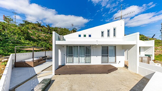 A modern white house with a flat roof, large windows, and a concrete patio. - Sunrise Vista Nanjo (Nanjo)