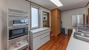 A compact kitchen with a microwave, oven, and dishwasher. There's a window, wooden cabinets, and a stainless steel refrigerator. - Sunrise Vista Nanjo (Nanjo)