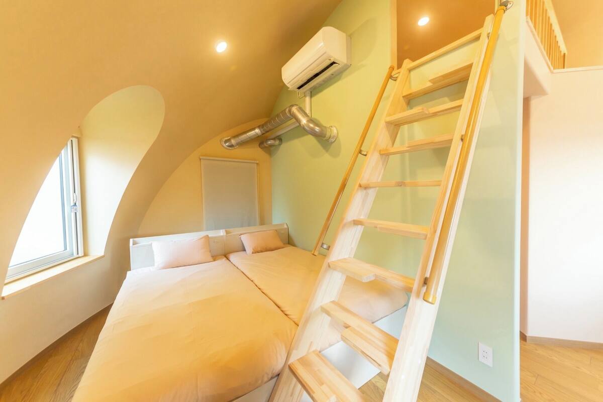 Un dormitorio con cama estilo altiloja, una escalera de madera, un equipo de aire acondicionado y una ventana.