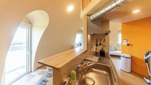 Une cuisine de taille réduite, dotée d’un plan de travail en bois, d’un évier en acier inoxydable et d’une fenêtre donnant sur un paysage urbain.