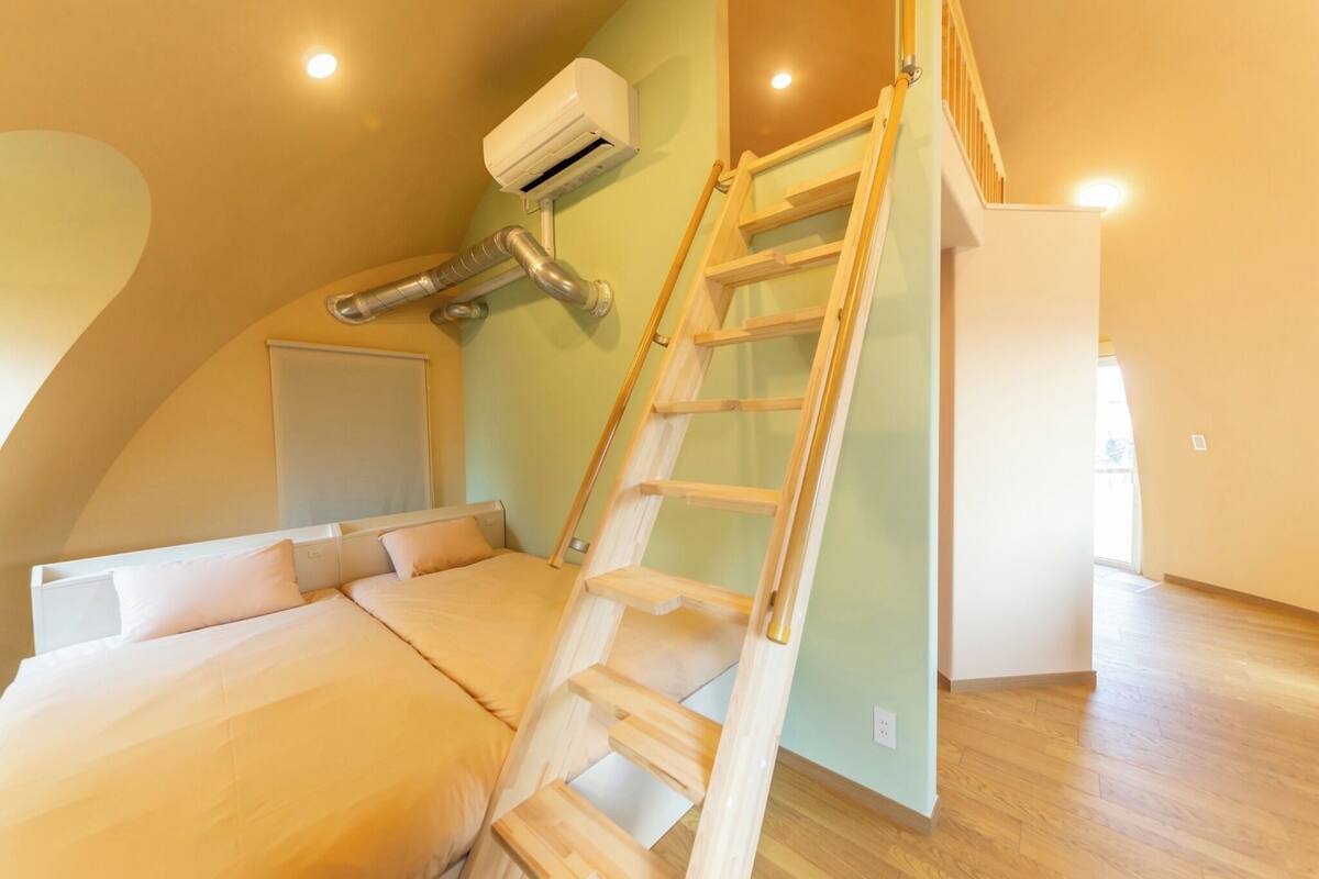 Un dormitorio con una escalera de madera, un equipo de aire acondicionado y una escalera que sube a un nivel superior.