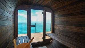 A wooden cabin with a wooden bench and a wooden bucket, a door leading to a balcony with a view of the sea. - Cliff Villa (Konan)