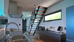 A modern kitchen with a stainless steel sink, a built-in microwave, and a sleek staircase. - Cliff Villa (Konan)