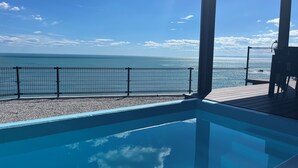 A pool with a view of the sea, a metal fence, and a wooden deck. - Cliff Villa (Konan)