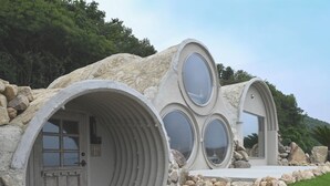 A unique house with a circular window design, stone exterior, and a door with a small balcony. - Covo Ushimado (Setouchi)