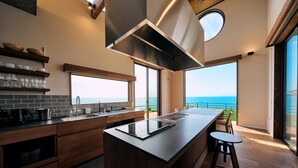 A modern kitchen with a large island, wooden cabinets, and a view of the ocean. - Private Villa Yuhimi ~sunset Hill~ (Aki)