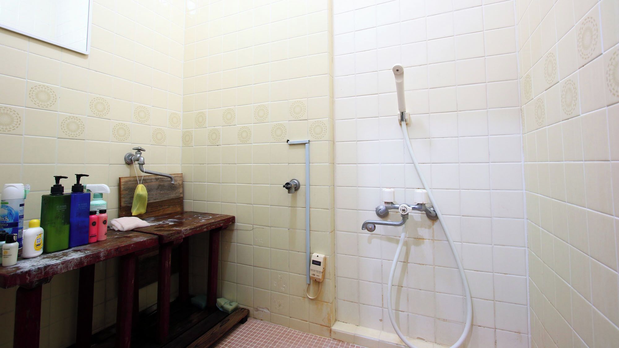 A bathroom with a shower, a sink with toiletries, and a mirror.