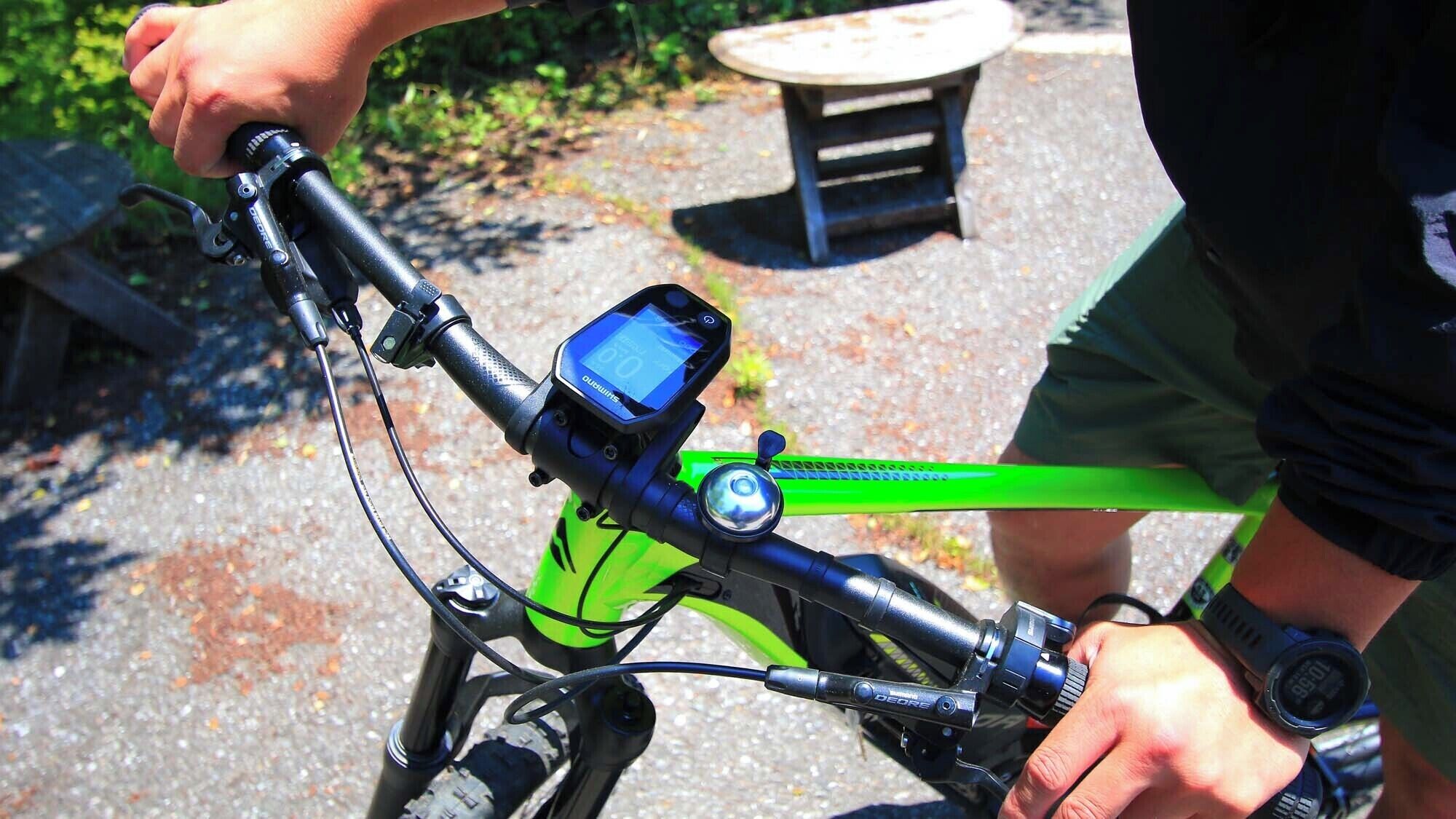 A bicycle with a digital display and a handlebar-mounted device, possibly a GPS or speedometer, in an outdoor setting.