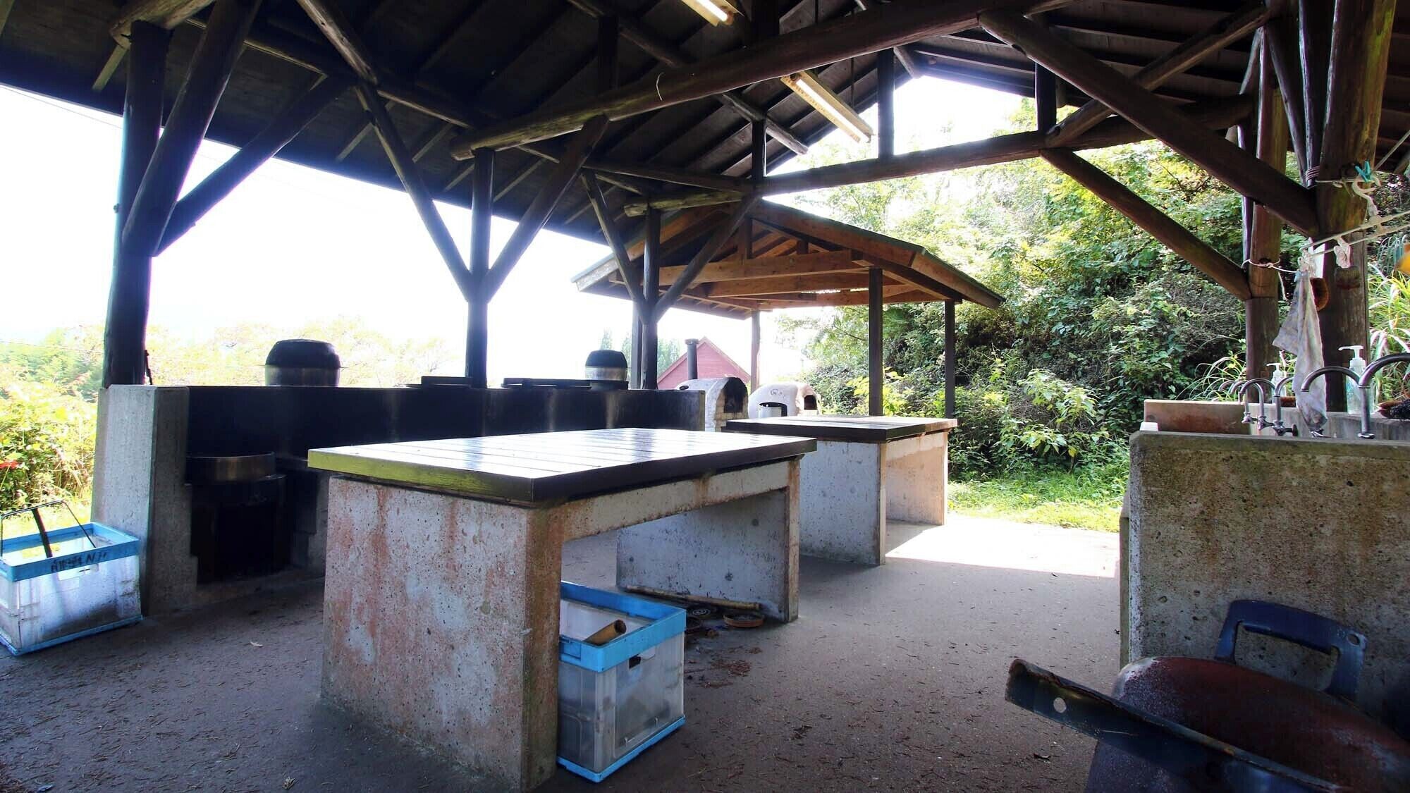An outdoor kitchen area with concrete countertops, a sink, and a grill.