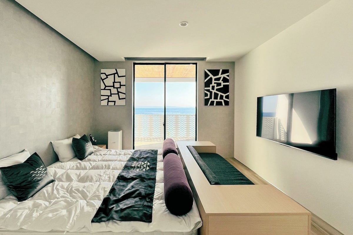 Una habitación de hotel moderna con una cama grande, un televisor y un balcón con vistas.