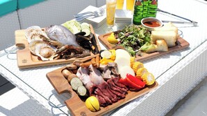 Ett bord med olika sorters mat och dryck, inklusive skaldjur, kött, grönsaker och bröd, upplagt på en vit duk.
