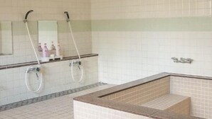 Um banheiro com uma banheira grande, duas pias com espelhos e piso revestido de azulejos.