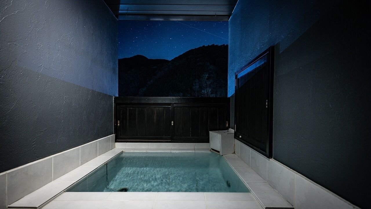 A modern indoor pool with a night sky mural on the ceiling, surrounded by dark walls and a tiled floor.