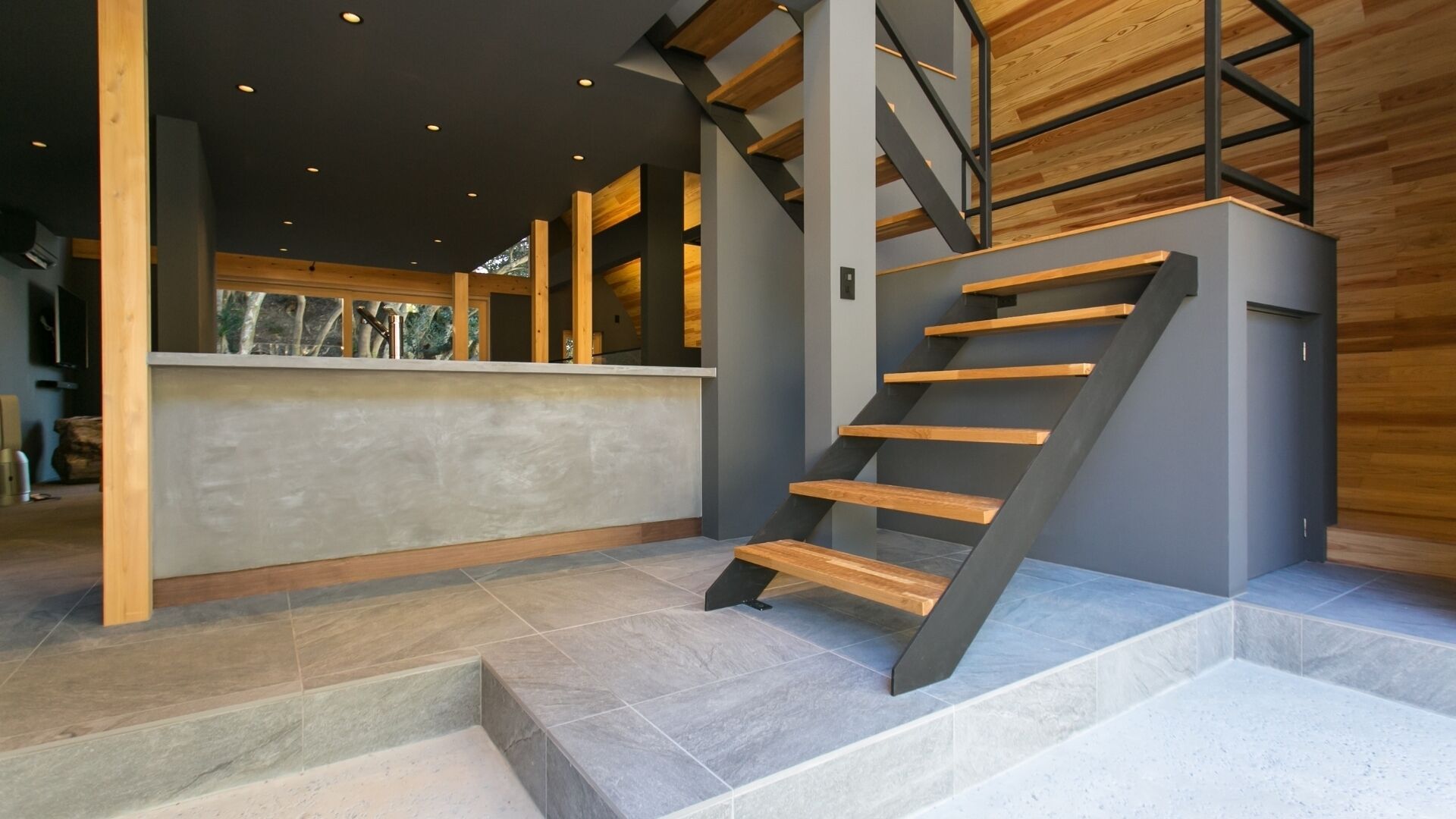 Un intérieur moderne avec un escalier, un comptoir d’accueil et une vue sur l’extérieur.