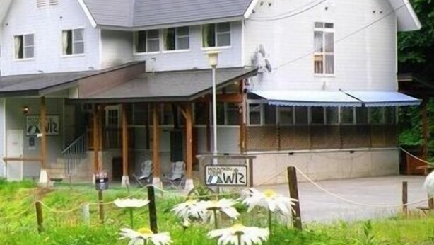 A two-story white building with a grey roof, a covered porch, and a sign that reads "WIZ". - Mountain Lodge Wiz (Omachi)
