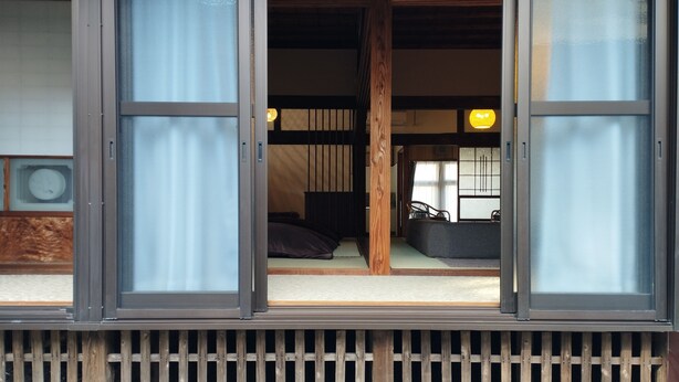 A traditional Japanese-style room with tatami flooring, a low wooden bed, and sliding doors. - Kominka Hashinoya (Yusui)