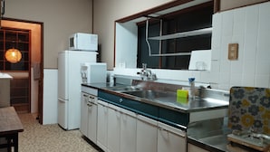 A compact kitchen with a sink, a microwave, and a refrigerator. - Kominka Hashinoya (Yusui)
