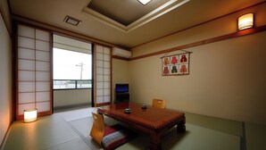 Ein traditioneller japanischer Raum mit Tatami-Bodenbelag, einem niedrigen Holztisch und verschiebbaren Türen.