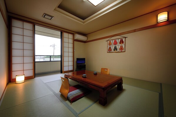 A traditional Japanese room with tatami flooring, a low wooden table, and sliding doors.