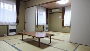 Una habitación japonesa tradicional con suelo de tatami, una mesa de madera y puertas correderas.