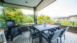 Eine Terrasse im Freien mit Grill, Tisch und Stühlen.