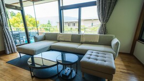 Ein modernes Wohnzimmer mit einer Eckcouch, zwei runden Couchtischen und Blick auf einen Balkon mit Gartenmöbeln.