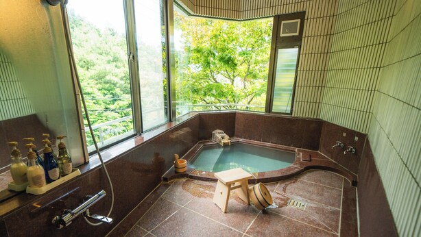 Ein Spa-Raum mit Whirlpool, einem hölzernen Hocker und einem Fenster mit Blick auf Bäume.